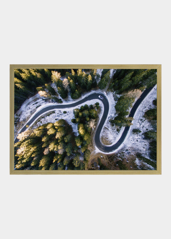 AERIAL VIEW OF SNOWY FOREST WITH A ROAD. CAPTURED FROM ABOVE WITH A DRONE. DOLOMITES - ITALY