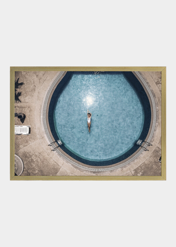 YOUNG ATTRACTIVE WOMAN FLOATS ON THE BACK IN THE ROUND BLUE POOL